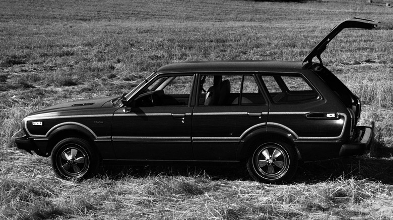 Black and white photo of a dark Corolla wagon parked in a desolate field
