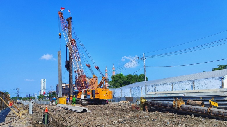 Heavy crane and pile driver setting pile in place
