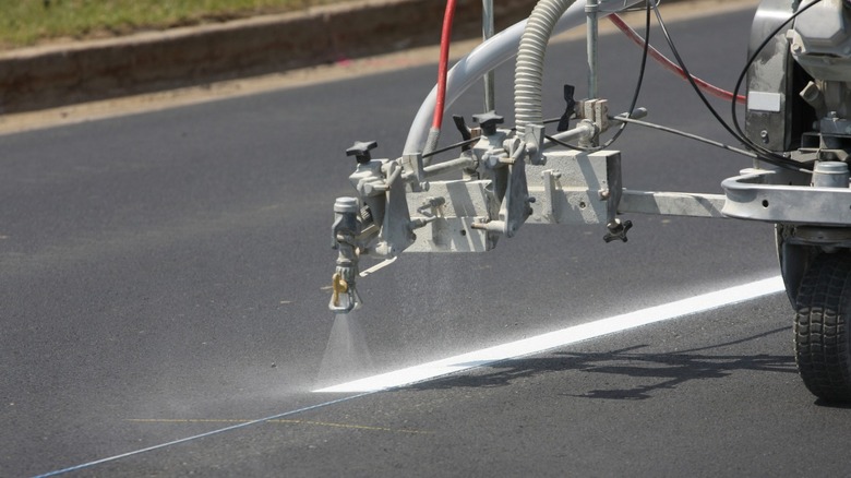 Road marker machine spraying white line on new asphalt road