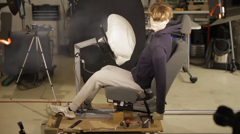 A screenshot from the video showing an actual airbag deploying and a DIY crash test dummy.