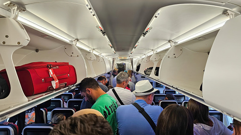 People crowd an aisle on a jet aircraft
