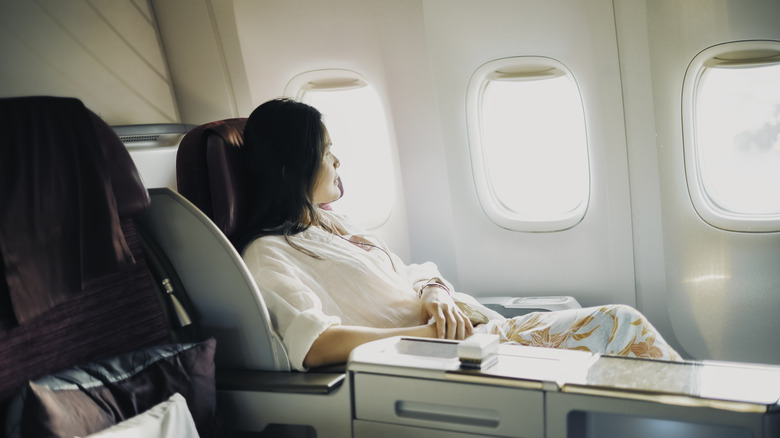 a woman reclines and looks out the window in first class