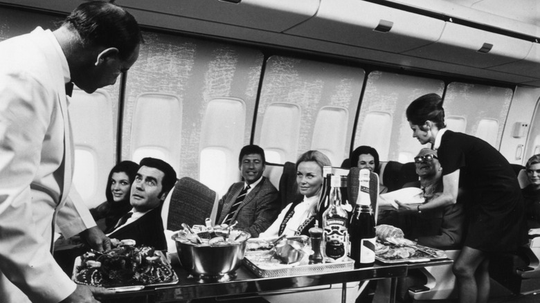 A black and white image of flight attendants serving drinks
