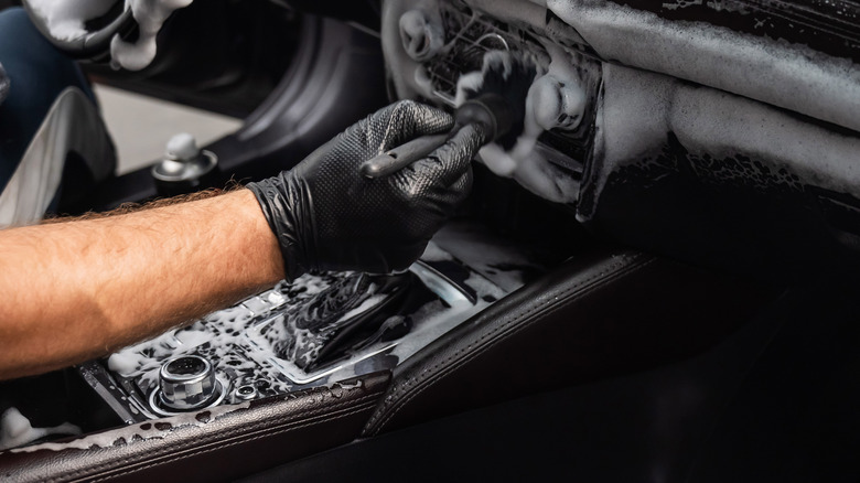 man deep cleans the interior of a car