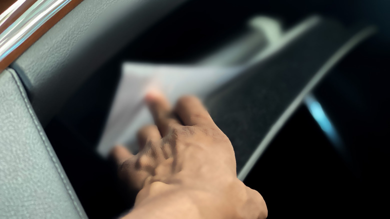 a woman reaches for something in her glove box