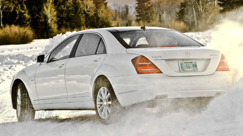 Rear 3/4 view of a white Mercedes-Benz S-Class drifting in snow