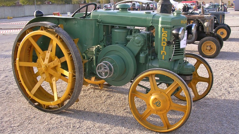 A green and yellow Landini hot-bulb tractor parked in a row at a classic tractor show