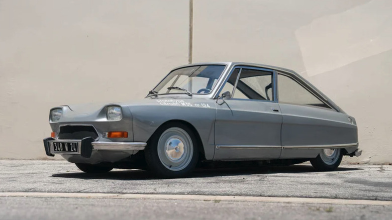 A driver-side profile of a grey 1970 Citroen M35 prototype in front of a beige building on faded blacktop.