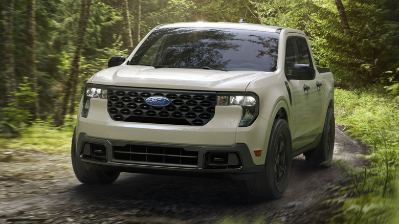 A Ford Maverick driving on a dirt road in a forest