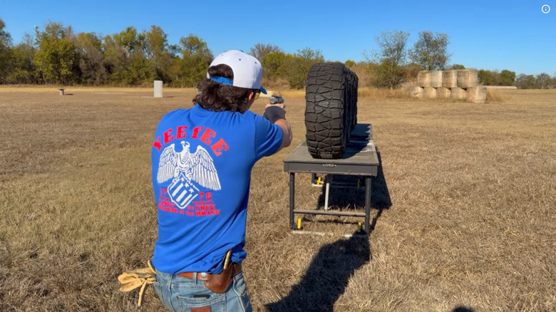 Parker Smith of Yee Yee Life preparing to shoot a .22 pistol at Nitto Mud Grappler tires