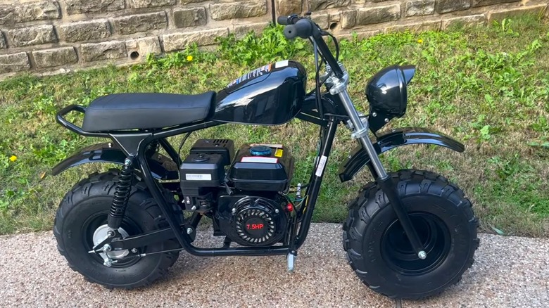 A black Massimo MB 200S mini bike parked on a driveway next to a lawn