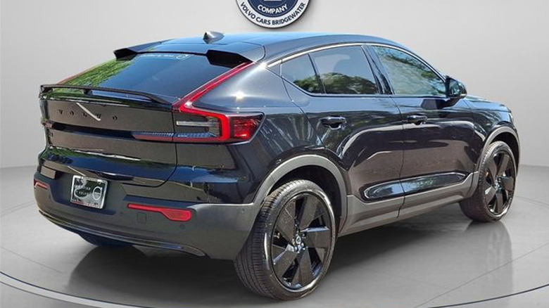 Rear three quarters shot of the all black EC40 parked on a gray floor with a gray background and a seal for Princeton Volvo at the top
