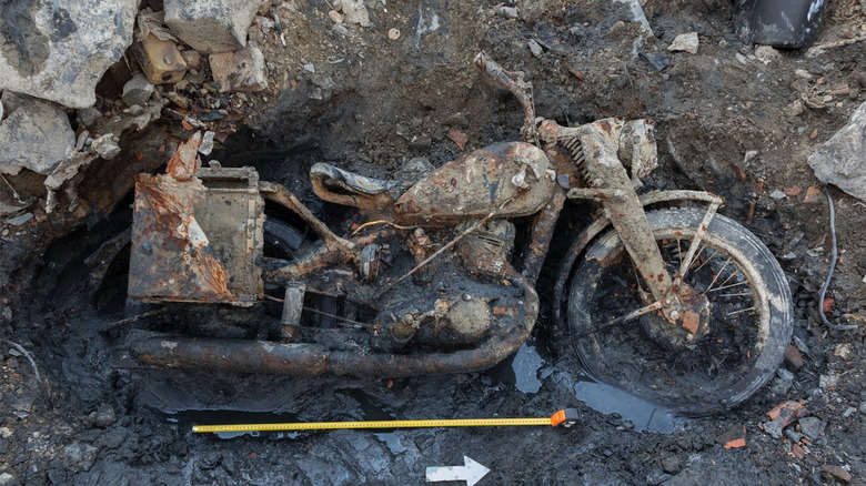 An unearthed motorcycle (DKW NZ 350-1) in surrounding mud and rock.