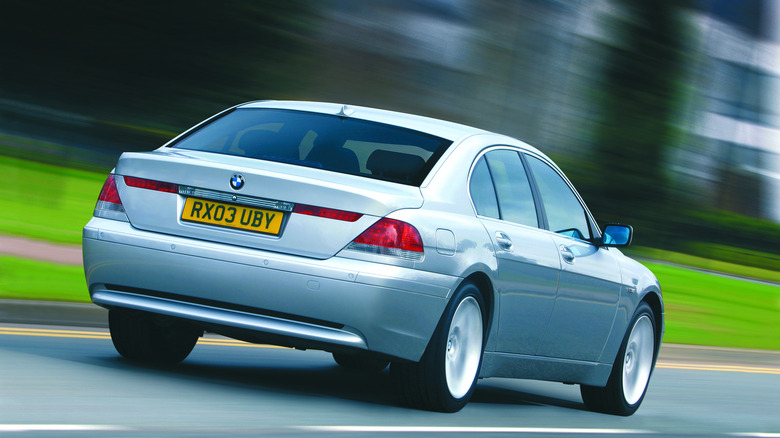 rear three-quarters shot of a silver 745i driving past blurred grass and trees