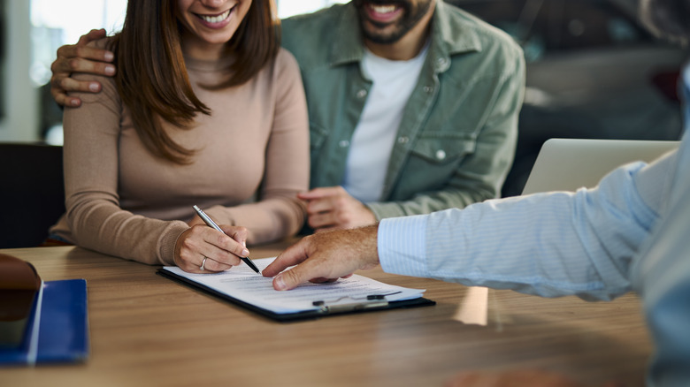Two people signing papers at a car dealership