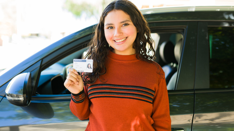 A woman holds up her driver's license.