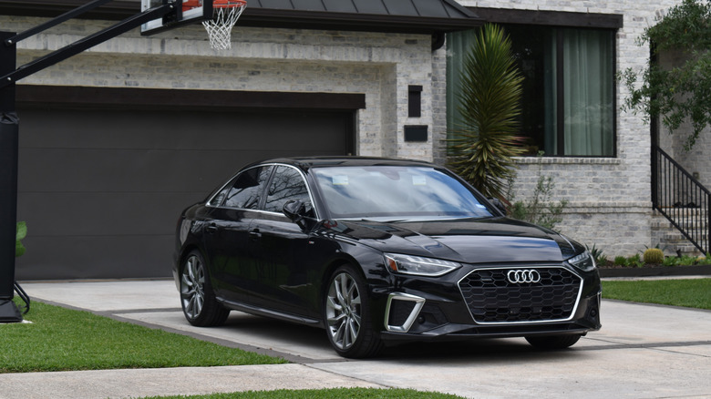 A black sedan is parked outside of a house.