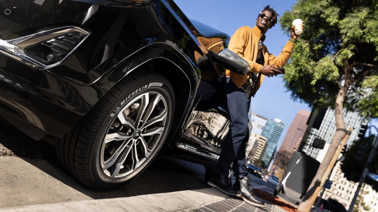 Man leaning against SUV with Michelin Defender tires