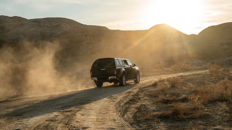 Rear 3/4 of pickup with bed topper on direct road
