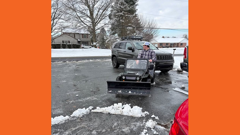 A man plowing a driveway with a miniature Jeep