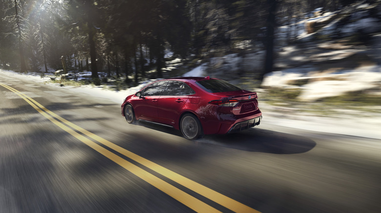Rear 3/4 of 2026 Toyota Corolla Hybrid sedan with snow in background