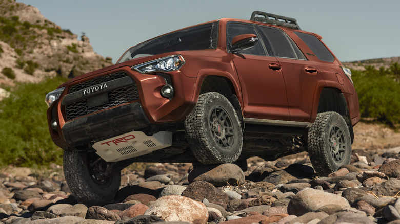 A bronze Toyota 4Runner driving over rocks