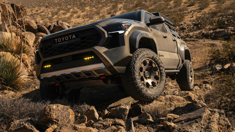A brown Toyota Tacoma driving over rocks