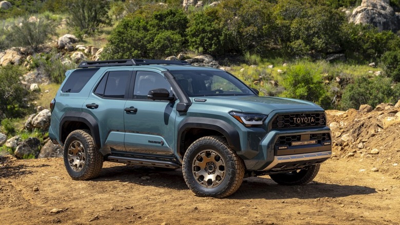 A teal Toyota 4Runner Trailhunter SUV with bronze wheels parked on a dirt off-road trail.