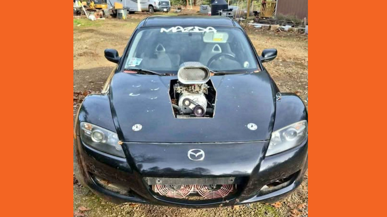 A black MAzda RX-8 with a supercharger sticking out the hood