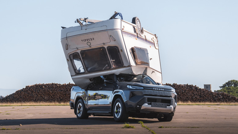 A grey Toyota Hilux with a caravan dropped on top of it