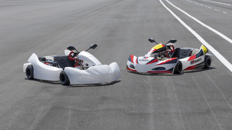 Two Toyota GT Karts parked side-by-side. The kart on the left features unbranded white panel, while the kart on the right is covered in red-and-black GR decals