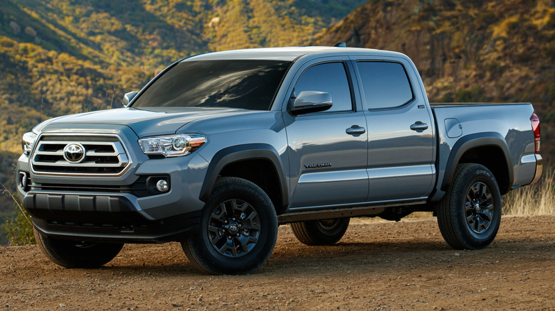 A 2021 Toyota Tacoma parked on a dirt surface with mountains in the background