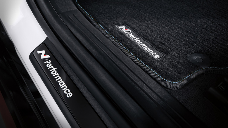 A close-up of the N Performance floor mats and scuff plate in a white car with a black interior