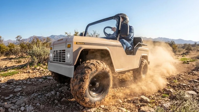 A cream-colored Massimo Mini Truck kicking up dirt with its LED headlights on.