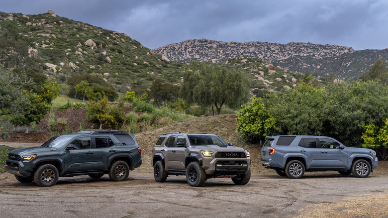 Three Toyota 4Runner models parked on a dirt road with mountains in the background
