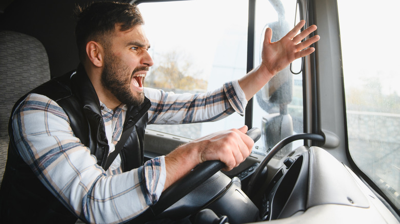 Angry man gesturing with his hand while driving a truck.