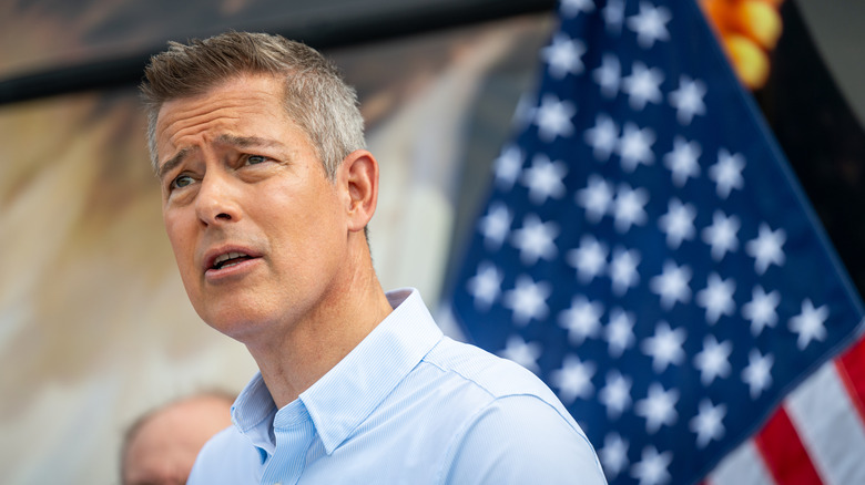 U.S. Transportation Secretary Sean Duffy Looks confused while standing in front of an American flag during a speech somewhere.