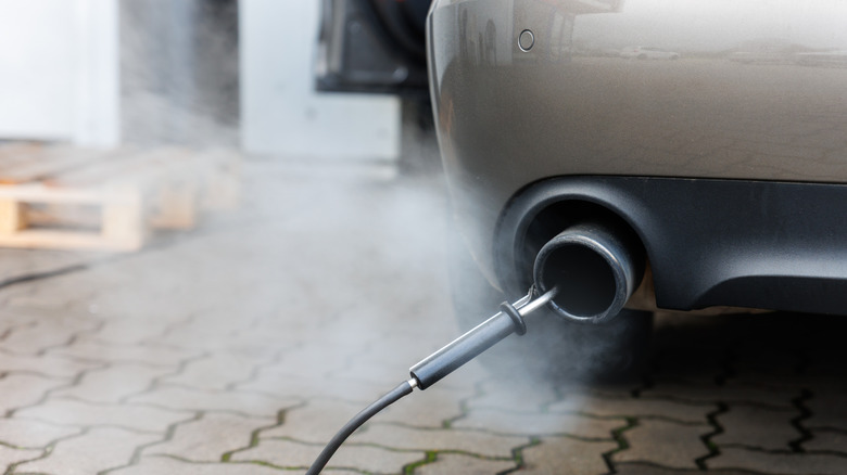 Close-up of an exhaust pipe with a sensor attached to it during an emissions test