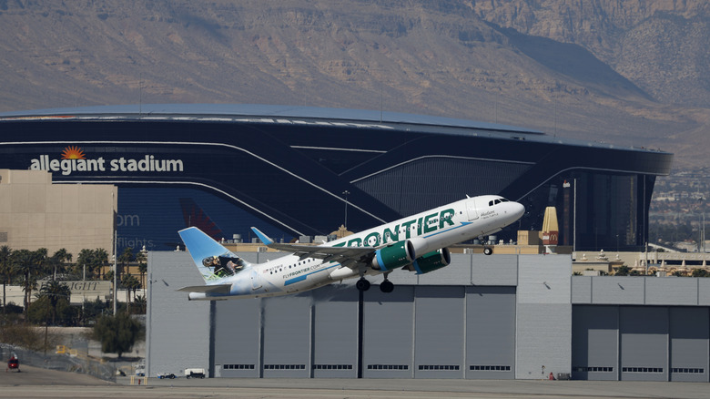 A Frontier Airlines Airbus A320 departs from Harry Reid International Airport en route to San Francisco with the Allegiant Stadium in the background on March 15, 2025 in Las Vegas, Nevada.