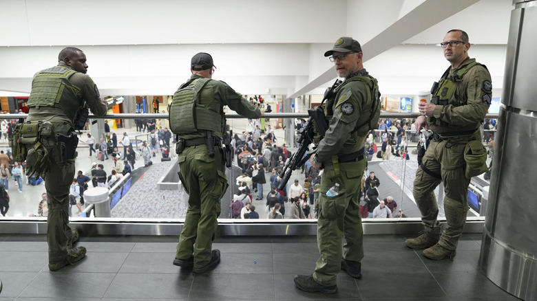 Officers look on as travelers stand in long lines at Atlanta Hartsfield-Jackson International Airport on March 23, 2026 in Atlanta, Georgia.