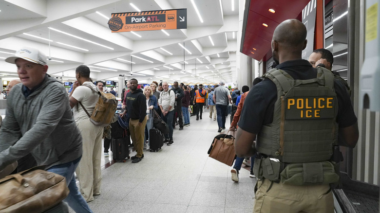 ATLANTA, GEORGIA - MARCH 23: Ice agents look on as travelers stand in long lines at Atlanta Hartsfield-Jackson International Airport on March 23, 2026 in Atlanta, Georgia.