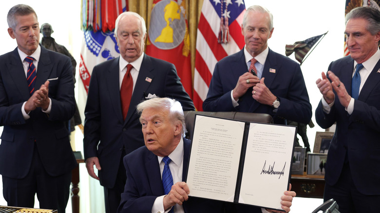U.S. President Donald Trump holds up a signed executive order alongside Secretary of Transportation Sean Duffy, Roger Penske, Chair of the Penske Corporation, Bud Denker, President of Penske Corporation, and U.S. Interior Secretary Doug Burgum, in the Oval Office of the White House on January 30, 2026 in Washington, DC.