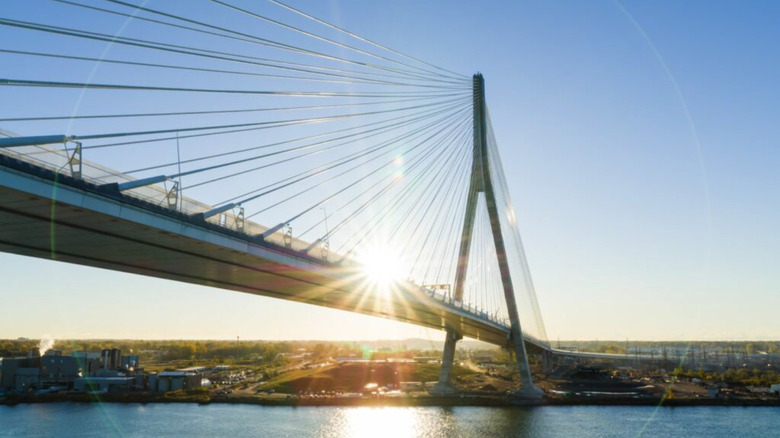 The Gordie Howe International Bridge lit from behind at sunset, spanning the Detroit River.