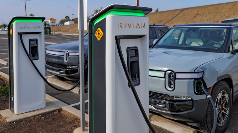 Rivian Adventure Network chargers charging a pair of R1S SUVs alongside Interstate 5