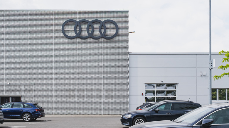 UDI logo on the side of a dealership building with cars in a parking lot