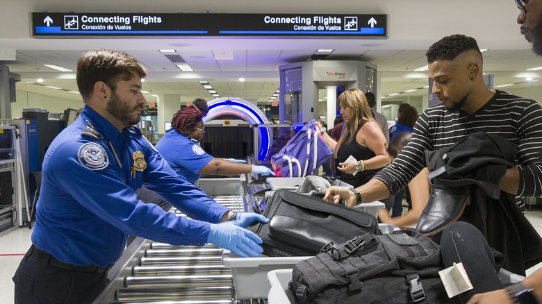 Transportation Security Administration (TSA) agents help travelers place their bags through the 3-D scanner at the Miami International Airport on May 21, 2019 in Miami, Florida.