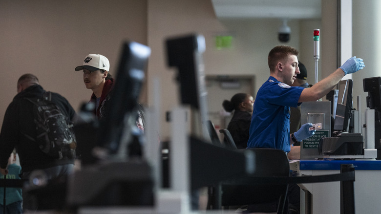 MINNEAPOLIS, MINNESOTA - MARCH 23: A TSA agent screens travelers at Minneapolis-St. Paul International Airport Terminal 2 on March 23, 2026 in Minneapolis, Minnesota. Travel disruptions continue as hundreds of TSA agents quit or work without pay during a partial government shutdown. U.S. President Donald Trump said ICE agents will be deployed to U.S. airports on Monday, with border czar Tom Homan in charge of the effort. (Photo by Stephen Maturen/Getty Images)