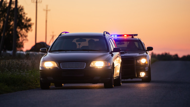 A driver getting pulled over by police car with flashing lights