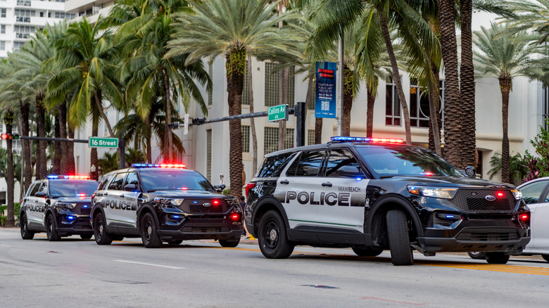 A line of three Ford Police Interceptor Utility SUVs with their lights on.