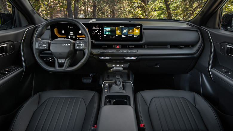 A wide shot of the all black interior of the new Seltos with green trees out the windshield